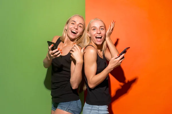 Retrato de una feliz sonrisa chicas casuales con teléfonos móviles sobre fondo de estudio —  Fotos de Stock