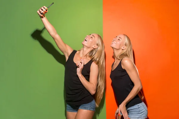 Retrato de una feliz sonrisa chicas casuales haciendo foto selfie por teléfono móvil aislado sobre fondo de estudio — Foto de Stock