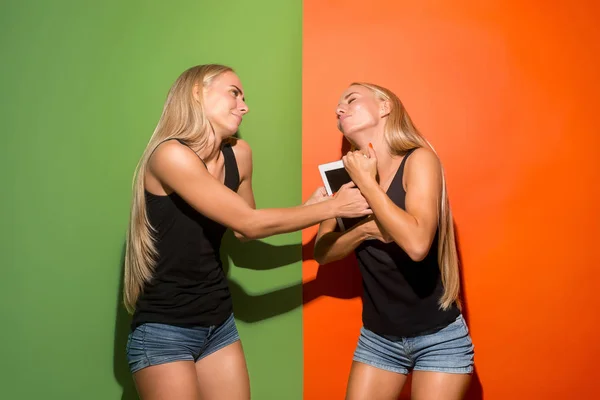 Imagen de dos jóvenes mujeres felices mirando a la cámara y sosteniendo el portátil . — Foto de Stock