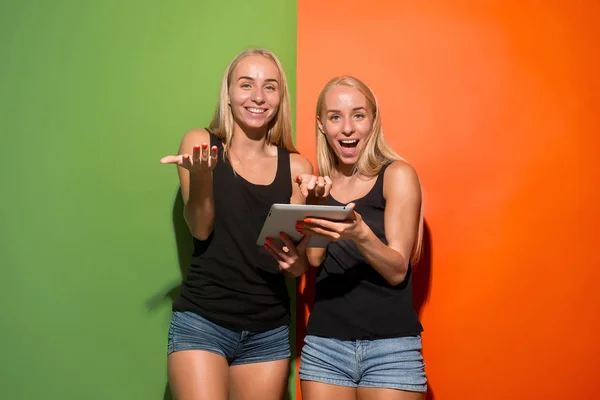 Image de deux jeunes femmes heureuses regardant la caméra et tenant un ordinateur portable . — Photo