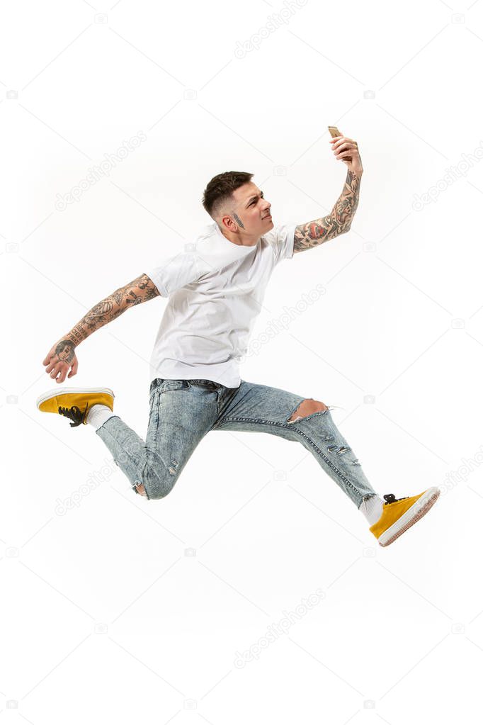 Full length of handsome young man taking selfie while jumping