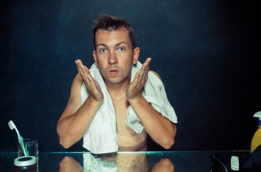 Yatak odası oturma sakalını tırmalamak aynanın önünde genç adam