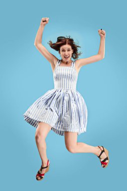 Hareketli bir özgürlük. Genç ve güzel kadın karşı mavi arka plan atlama