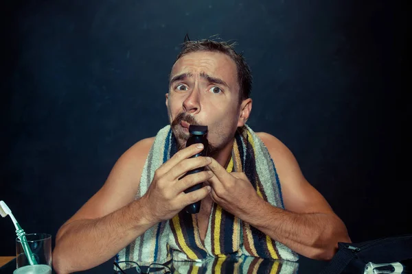 Joven en el dormitorio sentado frente al espejo rascándose la barba — Foto de Stock