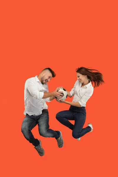 Das junge Paar als Fußballer hüpft und kickt den Ball im Studio auf einem roten Teppich — Stockfoto