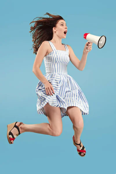 Mulher bonita pulando com megafone isolado sobre fundo azul — Fotografia de Stock