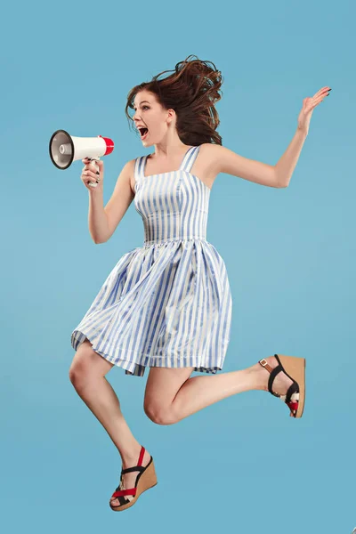 Mulher bonita pulando com megafone isolado sobre fundo azul — Fotografia de Stock