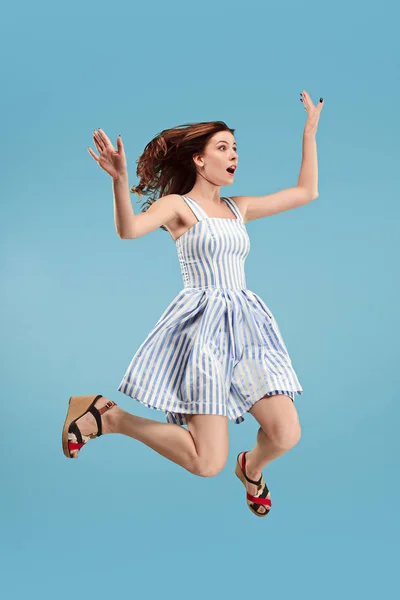 Szabadság mozgó. Csinos, fiatal nő, ugrás, kék háttérrel — Stock Fotó