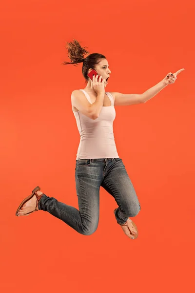 Pełna długość dość młoda kobieta z telefonu komórkowego podczas skoków — Zdjęcie stockowe