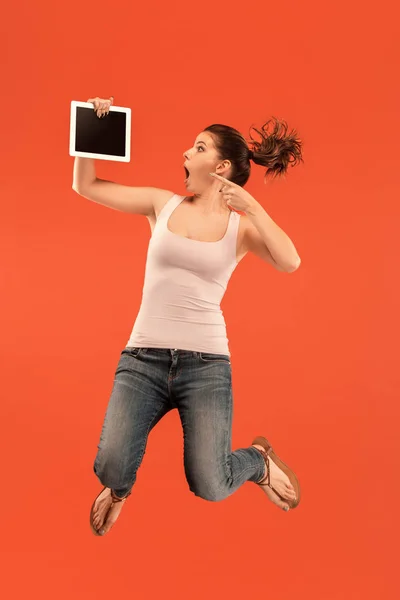Зображення молодої жінки на синьому фоні за допомогою ноутбука або планшетного пристрою під час стрибків . — стокове фото