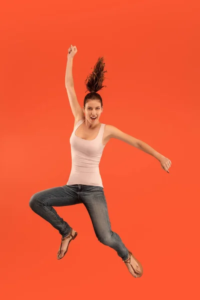 Свобода в русі. Красива молода жінка стрибає на помаранчевому фоні — стокове фото