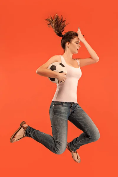 승리에 전달 합니다. 점프 하 고 빨간색에 스튜디오에서 공을 차고 축구 축구 선수로 서 젊은 여자 — 스톡 사진