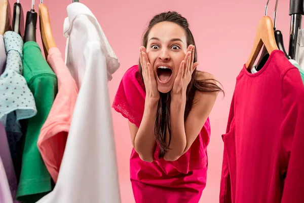 La joven chica bonita mirando vestidos y probarlo mientras elige en la tienda — Foto de Stock