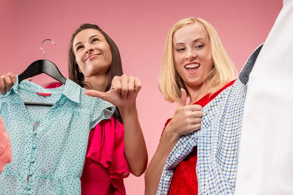 De twee jonge mooie meisjes jurken kijken en proberen op het terwijl het kiezen van bij shop — Stockfoto