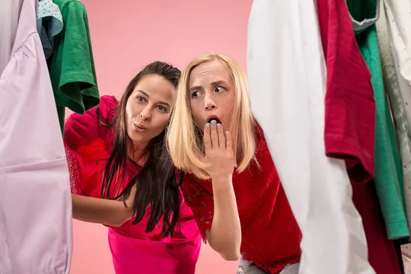 Las dos chicas guapas jóvenes mirando vestidos y probarlo al elegir en la tienda — Foto de Stock