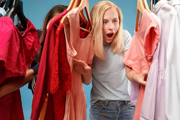 Las dos chicas guapas jóvenes mirando vestidos y probarlo al elegir en la tienda — Foto de Stock