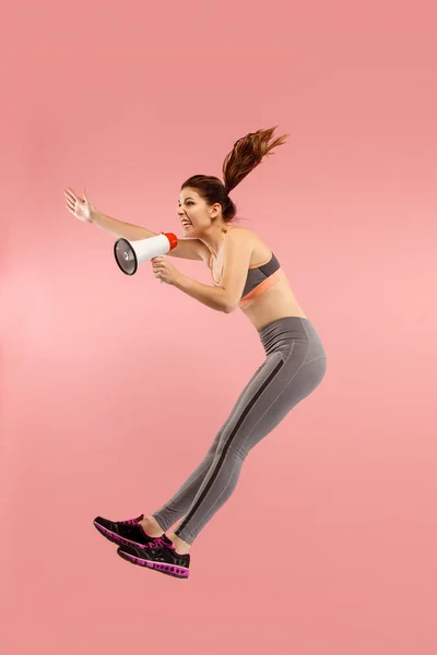 Schöne junge Frau springt mit Megafon isoliert über rotem Hintergrund — Stockfoto