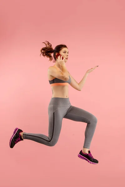 Full length of pretty young woman with mobile phone while jumping — Stock Photo, Image