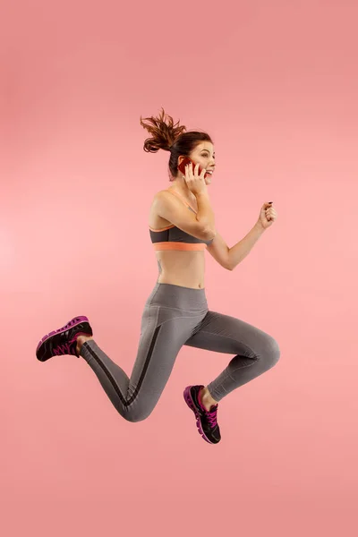 Full length of pretty young woman with mobile phone while jumping — Stock Photo, Image