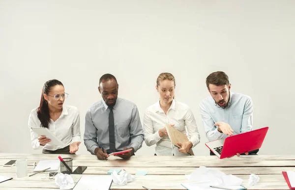 Hombres y mujeres jóvenes sentados en la oficina y trabajando en computadoras portátiles. Concepto de emociones —  Fotos de Stock