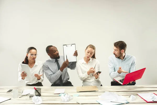 Hombres y mujeres jóvenes sentados en la oficina y trabajando en computadoras portátiles. Concepto de emociones — Foto de Stock