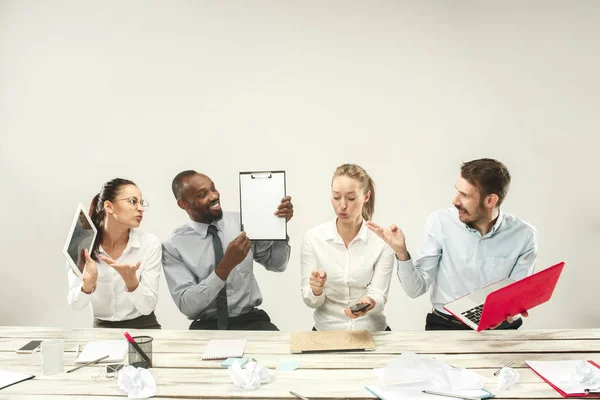 Hombres y mujeres jóvenes sentados en la oficina y trabajando en computadoras portátiles. Concepto de emociones — Foto de Stock