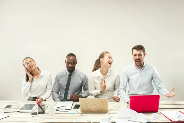 Hombres y mujeres jóvenes sentados en la oficina y trabajando en computadoras portátiles. Concepto de emociones — Foto de Stock