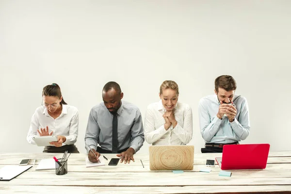 Hombres y mujeres jóvenes sentados en la oficina y trabajando en computadoras portátiles. Concepto de emociones —  Fotos de Stock