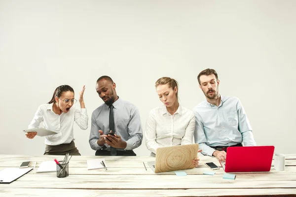 Hombres y mujeres jóvenes sentados en la oficina y trabajando en computadoras portátiles. Concepto de emociones — Foto de Stock