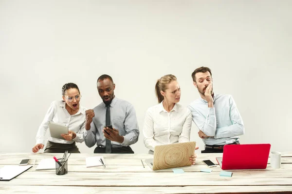 Young men and women sitting at office and working on laptops. Emotions concept — Stock Photo, Image