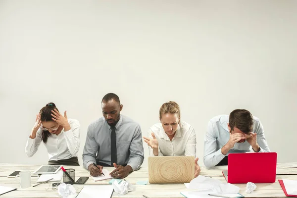 Hombres y mujeres jóvenes sentados en la oficina y trabajando en computadoras portátiles. Concepto de emociones — Foto de Stock