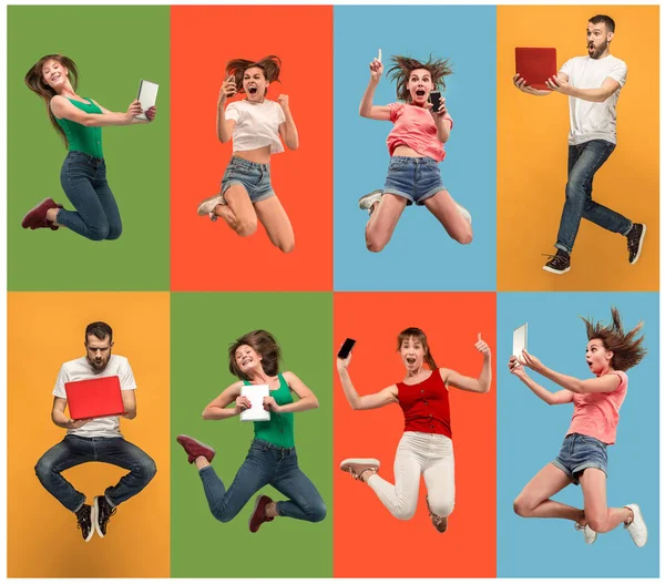 The happy young jumping women and man with laptops and phone