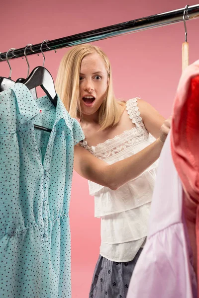 La joven chica bonita mirando vestidos y probarlo mientras elige en la tienda — Foto de Stock