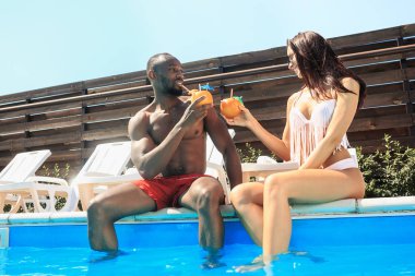 Oynama ve yaz tatillerinde bir yüzme havuzunda rahatlatıcı arkadaş grubu