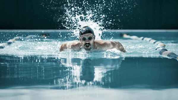 Dynamischer und fitter Schwimmer mit Schirmmütze, der den Schmetterlingsschlag ausführt — Stockfoto