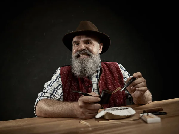 Бородатый человек забивает табак в трубу — стоковое фото