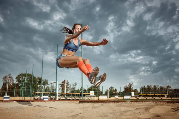 Kvinnliga idrottare utför en längdhopp under en tävling — Stockfoto