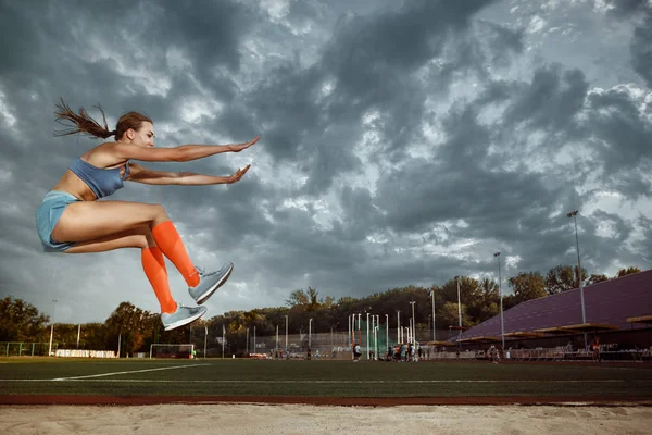 Atleta feminina realizando um salto em distância durante uma competição — Fotografia de Stock