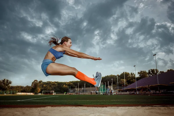 Atleta femenina realizando un salto de longitud durante una competición — Foto de Stock