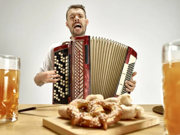 Людина в традиційному баварському одязі грає на акордеоні. Октоберфест — стокове фото
