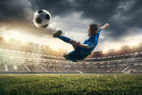 Niño con pelota de fútbol haciendo patada voladora en el estadio —  Fotos de Stock