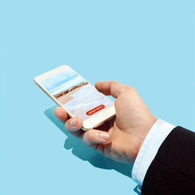Otel rezervasyon uygulaması ile smartphone üzerinde plaj ve mavi gökyüzü tutan el
