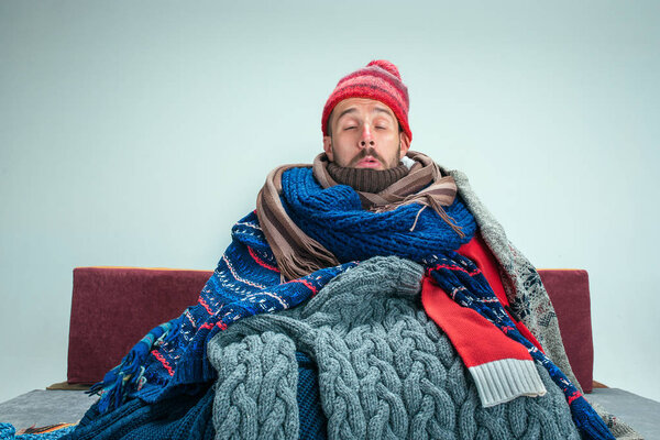 Bearded Man with Flue Sitting on Sofa at Home. Healthcare Concepts.