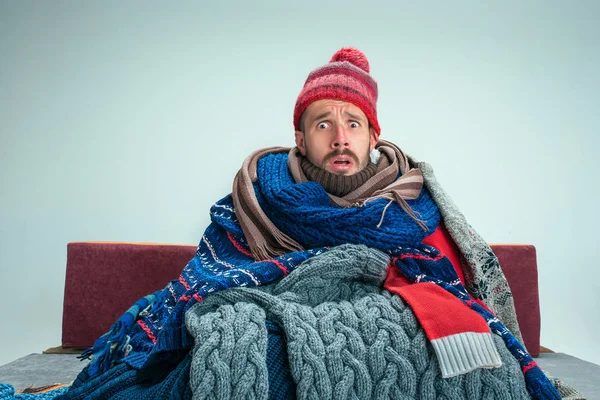 Hombre barbudo con chimenea sentado en el sofá en casa. Conceptos sanitarios . — Foto de Stock