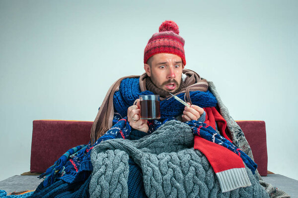 Bearded Man with Flue Sitting on Sofa at Home. Healthcare Concepts.