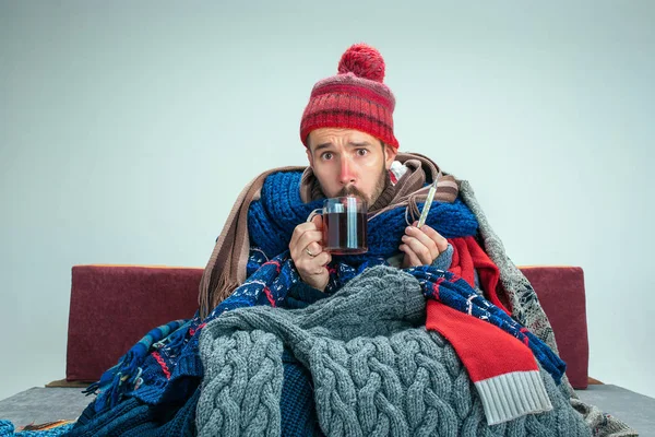 Hombre barbudo con chimenea sentado en el sofá en casa. Conceptos sanitarios . — Foto de Stock