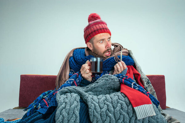 Bearded Man with Flue Sitting on Sofa at Home. Healthcare Concepts.