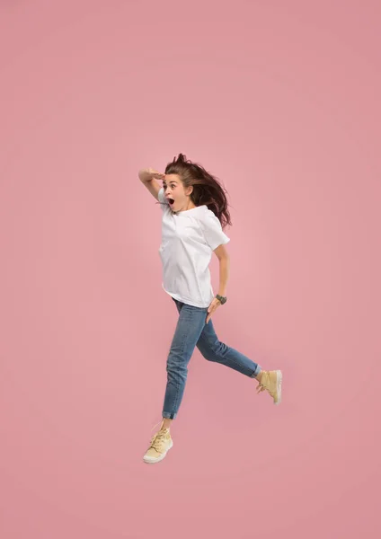 Vrijheid in beweging. Mooie jonge vrouw springen tegen roze achtergrond — Stockfoto