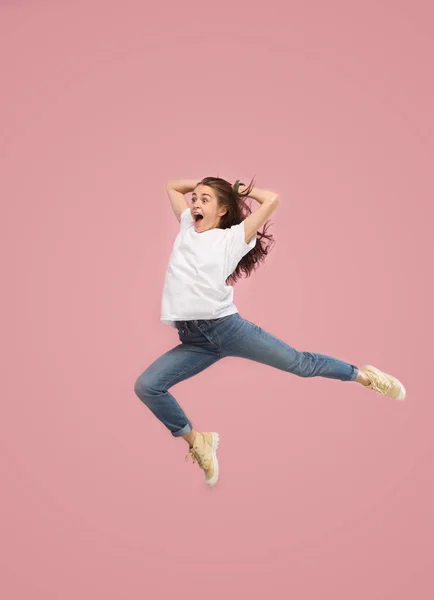 Liberdade em movimento. Mulher muito jovem pulando contra fundo rosa — Fotografia de Stock