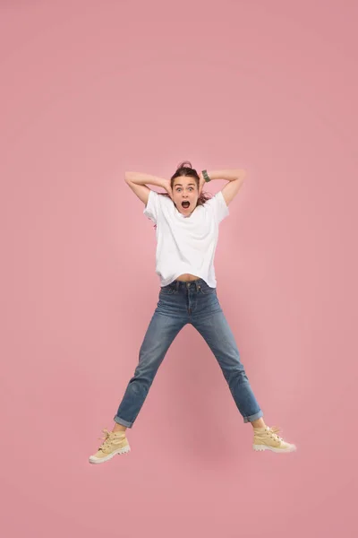 Vrijheid in beweging. Mooie jonge vrouw springen tegen roze achtergrond — Stockfoto